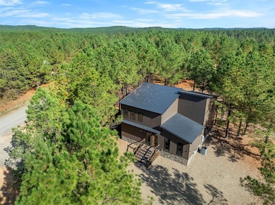 Aerial view of property and surrounding area with a forest