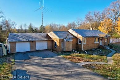 Ranch-style house featuring driveway, a garage, brick siding, and a chimney