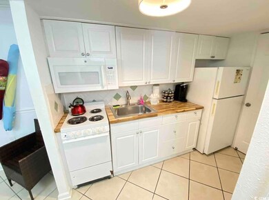 Kitchen with white appliances, a sink, white cabinets, light countertops, and decorative backsplash
