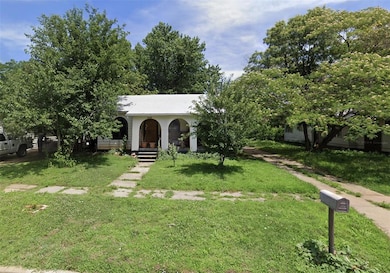 View of property hidden behind natural elements featuring a porch, a front yard, and metal roof