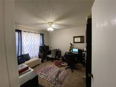 Carpeted office with ceiling fan and a textured ce