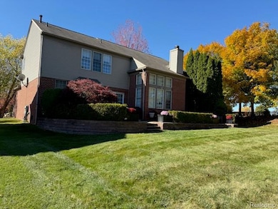 Rear view of property featuring a yard, a chimney, and brick siding