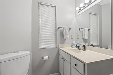 Half bathroom featuring toilet, vanity, and basebo