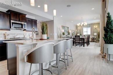 Kitchen with stainless steel microwave, light countertops, dark brown cabinetry, a chandelier, and recessed lighting