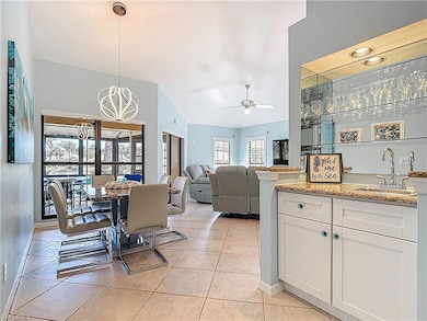Dining room with light tile patterned flooring, a ceiling fan, bar, a chandelier, and baseboards