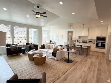 Living area with lofted ceiling, light wood finished floors, a textured ceiling, and recessed lighting