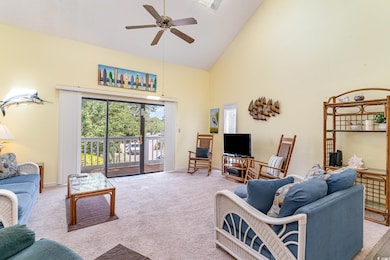 Carpeted living area featuring high vaulted ceiling and a ceiling fan