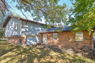 View of side of property featuring brick siding and a yard