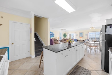 Kitchen featuring freestanding refrigerator, crown molding, stove, light tile patterned floors, and a center island