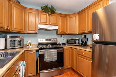 Kitchen with brown cabinetry, a textured ceiling, 