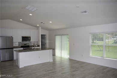 Kitchen with stainless steel appliances, lofted ceiling, decorative backsplash, white cabinets, and healthy amount of natural light