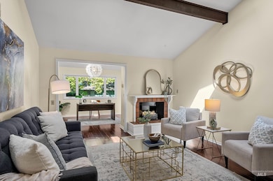 Living room with wood finished floors, a chandelier, and a tiled fireplace