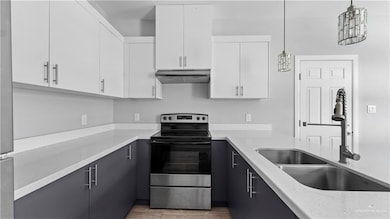Kitchen featuring stainless steel appliances, white cabinetry, under cabinet range hood, and decorative light fixtures