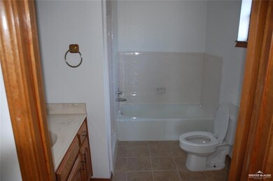 Bathroom with vanity, light tile patterned floors, and a tub to relax in