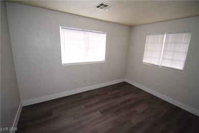 Empty room with baseboards and dark wood-style floors