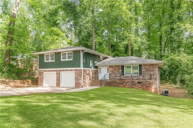 Split level home with concrete driveway, a front lawn, brick siding, and an attached garage
