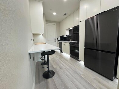 Kitchen featuring black appliances, light wood-ty