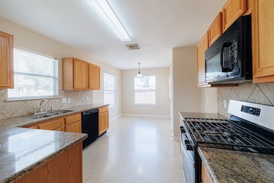 Kitchen features granite countertops, tile backsplash, and ample cabinet storage.