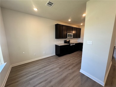 Kitchen with electric range, dark wood-style floors, backsplash, stainless steel microwave, and recessed lighting