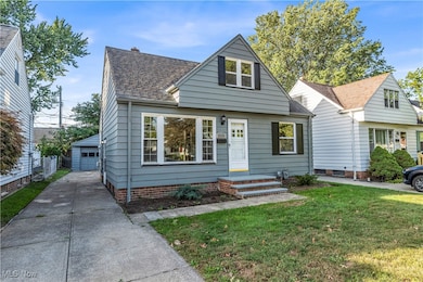View of front of property featuring an outdoor structure, roof with shingles, and a garage