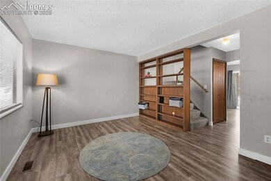 Sitting room with wood finished floors, a textured ceiling, stairway, and baseboards