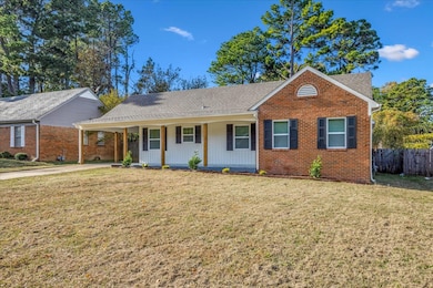 View of front of house featuring covered porch, a shingled roof, concrete driveway, a carport, and brick siding