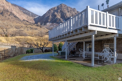 View of yard with central AC unit, a deck with mountain view, and a patio