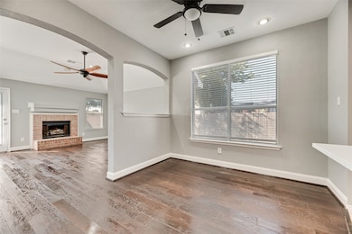Unfurnished living room with ceiling fan, dark wood finished floors, a brick fireplace, and recessed lighting
