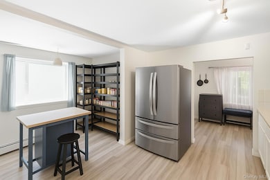 Kitchen with freestanding refrigerator, light wood-style flooring, a breakfast bar area, and light countertops