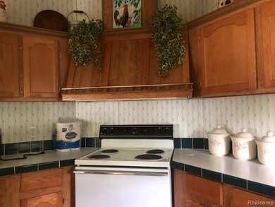 Kitchen with white range with electric stovetop, brown cabinetry, and wallpapered walls