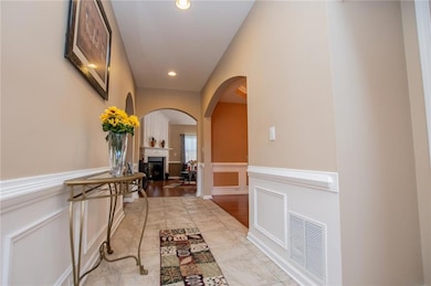 Corridor with arched walkways, a decorative wall, wainscoting, and recessed lighting