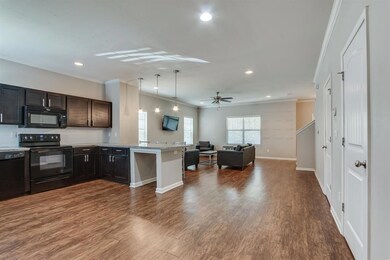Kitchen featuring black appliances, open floor plan, crown molding, a peninsula, and a ceiling fan