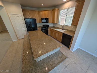 Kitchen with black appliances, recessed lighting, light tile patterned flooring, light stone countertops, and a center island
