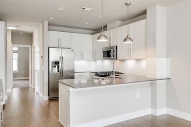 Kitchen featuring stainless steel appliances, a peninsula, wood finished floors, tasteful backsplash, and recessed lighting