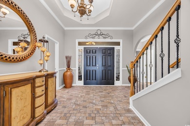 Foyer entrance featuring a tray ceiling, crown molding, and an Sally Stowe Designer Chandelier