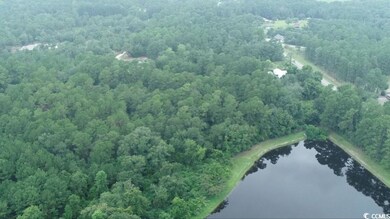 Aerial view of property's location with a forest and a nearby body of water