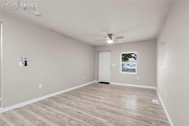 Unfurnished room featuring ceiling fan, a smoke detector, light wood finished floors, and baseboards