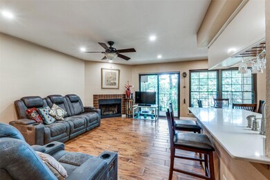 Living room with wood-type flooring, ceiling fan, and a brick fireplace