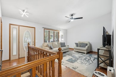 Bright and welcoming living room featuring vaulted ceilings and abundant natural light. Highlights include updated lighting fixtures, neutral walls, and warm laminate wood floors that flow throughout the space.