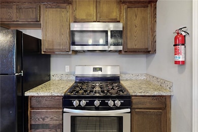 Kitchen with light stone counters and appliances w