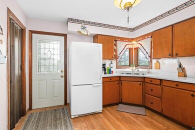 Kitchen with freestanding refrigerator, a sink, light countertops, and light wood-style flooring
