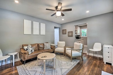 Living room with ceiling fan, baseboards, dark wo