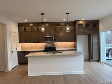 Kitchen featuring decorative backsplash, a center island with sink, light wood-style floors, stainless steel appliances, and recessed lighting
