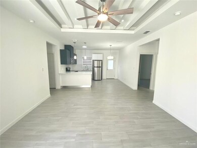 Unfurnished living room featuring ceiling fan and baseboards