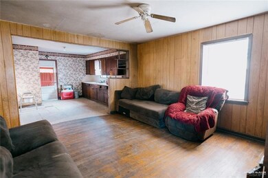 Living room with ceiling fan, wooden walls, and light hardwood / wood-style flooring