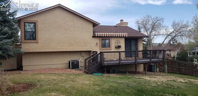 Rear view of house with a wooden deck, central AC, a yard, fence, and a chimney