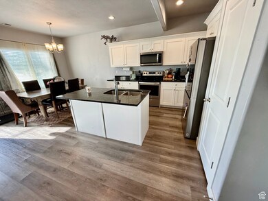 Kitchen featuring a center island with sink, appliances with stainless steel finishes, white cabinets, light wood-style flooring, and recessed lighting