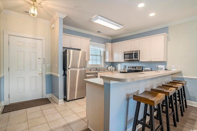 Kitchen featuring stainless steel appliances, a peninsula, baseboards, a kitchen breakfast bar, and crown molding