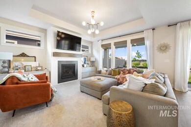 Elegant living space with a gas fireplace, chandelier, and a tray ceiling.