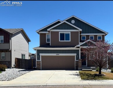 Craftsman house featuring board and batten siding, fence, a garage, driveway, and stone siding